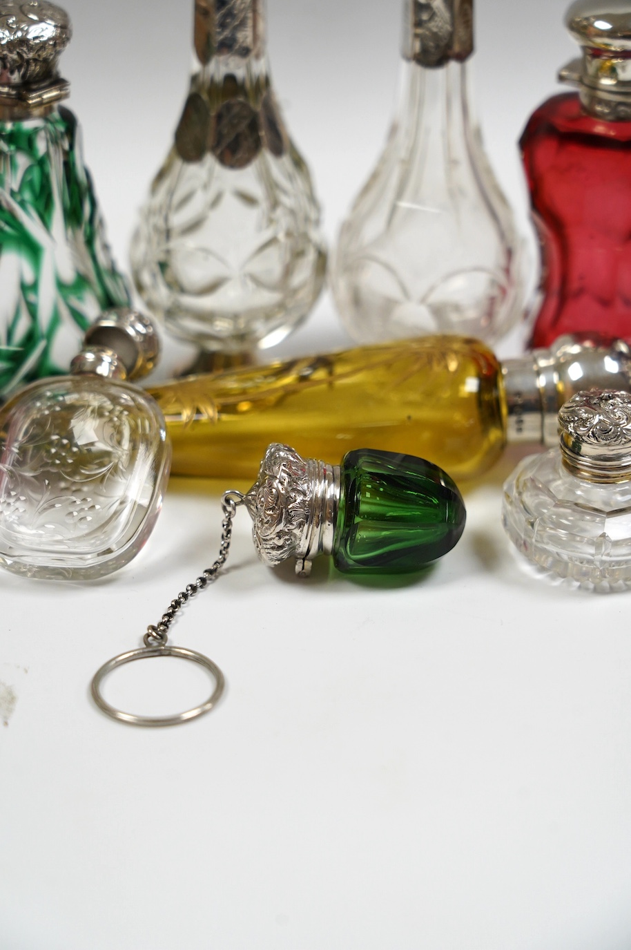 A collection of ten assorted Victorian and later silver or white metal mounted glass scent bottles, including teardrop shaped by Saunders & Shepherd, Birmingham, 1884, 12.7cm. Condition - poor to fair to good